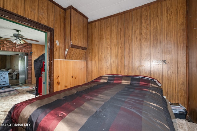 carpeted bedroom featuring ceiling fan and wood walls