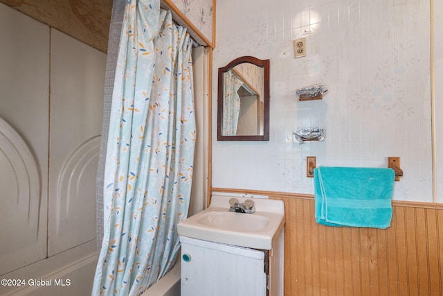 bathroom featuring vanity, wood walls, and shower / bathtub combination with curtain