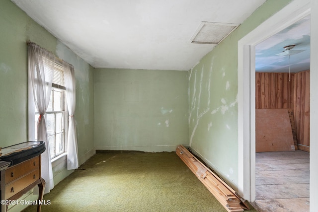 unfurnished room featuring light carpet and wood walls