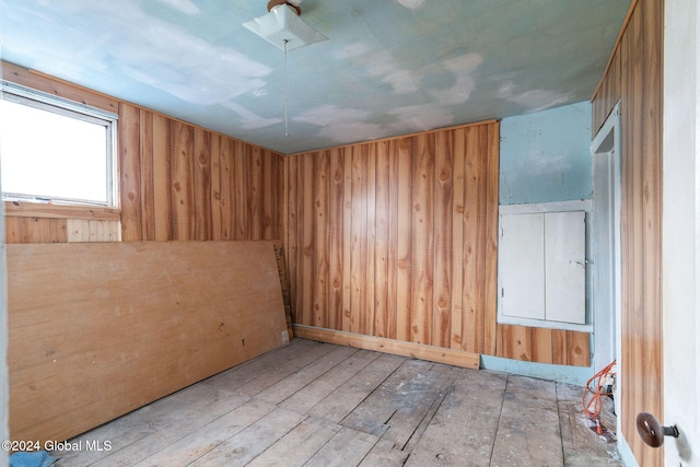 empty room with wood walls and light wood-type flooring