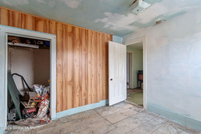 unfurnished bedroom featuring a closet and wood walls