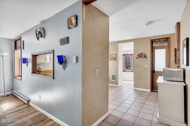 corridor with a textured ceiling, light hardwood / wood-style flooring, and baseboard heating