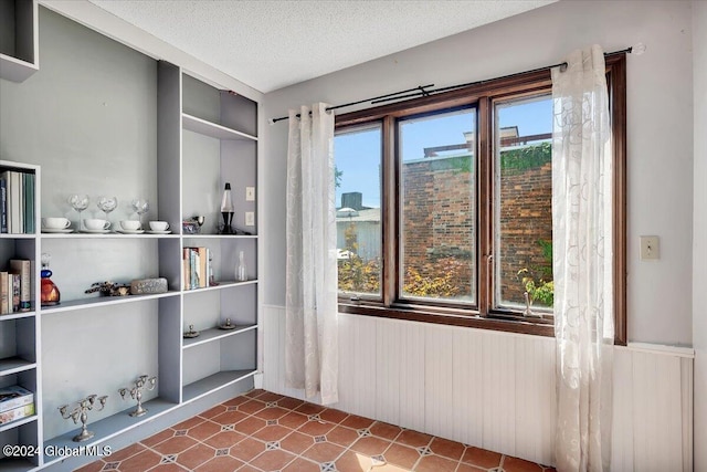 unfurnished room with wood walls, a textured ceiling, and plenty of natural light