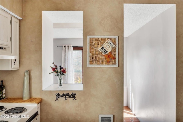 hall with a textured ceiling and light tile patterned floors