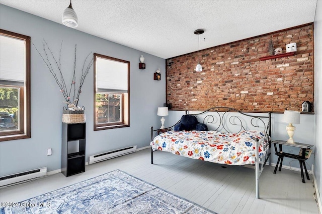 bedroom featuring a baseboard radiator, a textured ceiling, and brick wall