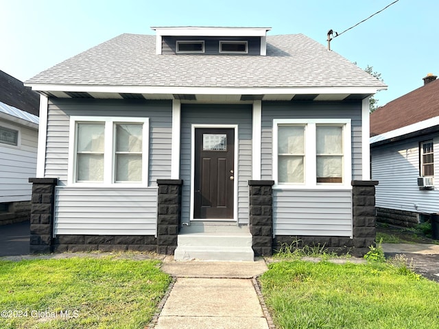 bungalow-style house with cooling unit and a front lawn