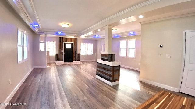 living room with hardwood / wood-style floors, a tray ceiling, ornamental molding, and decorative columns