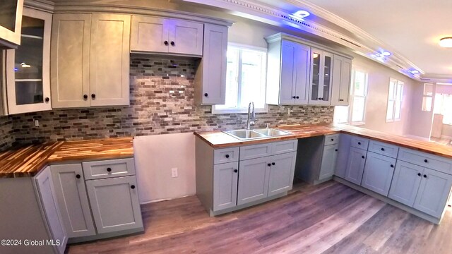 kitchen with crown molding, wooden counters, sink, and backsplash