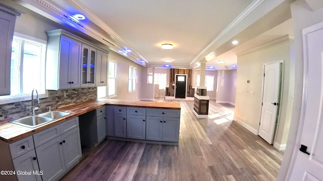 kitchen featuring decorative columns, ornamental molding, butcher block counters, and sink