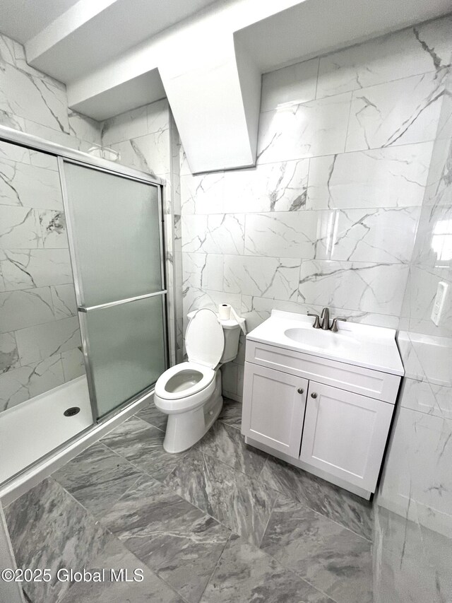 bathroom with vanity, toilet, tile walls, and a shower with shower door