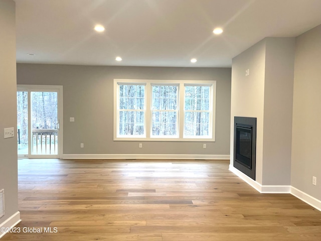 unfurnished living room featuring light hardwood / wood-style flooring and plenty of natural light