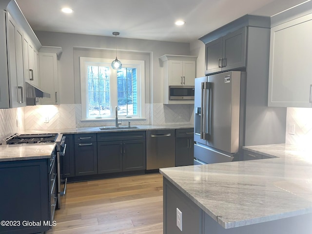 kitchen featuring sink, wall chimney exhaust hood, decorative backsplash, light hardwood / wood-style floors, and stainless steel appliances