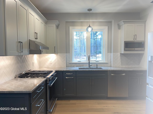 kitchen with sink, light wood-type flooring, backsplash, and appliances with stainless steel finishes