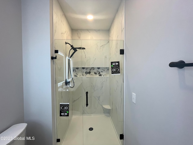 bathroom featuring a shower with shower door and toilet