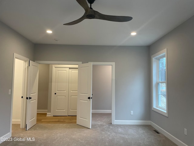 unfurnished bedroom with ceiling fan, light carpet, a closet, and multiple windows