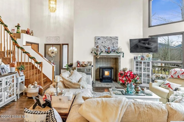 living room featuring a towering ceiling, a fireplace, a wood stove, and wood-type flooring