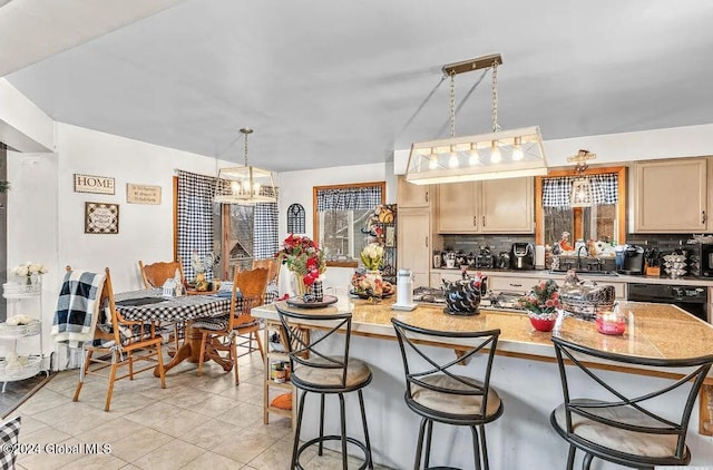 kitchen with tasteful backsplash, light brown cabinets, a kitchen breakfast bar, a notable chandelier, and light tile patterned flooring