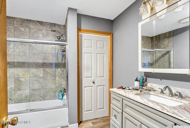 bathroom with hardwood / wood-style floors, combined bath / shower with glass door, and vanity