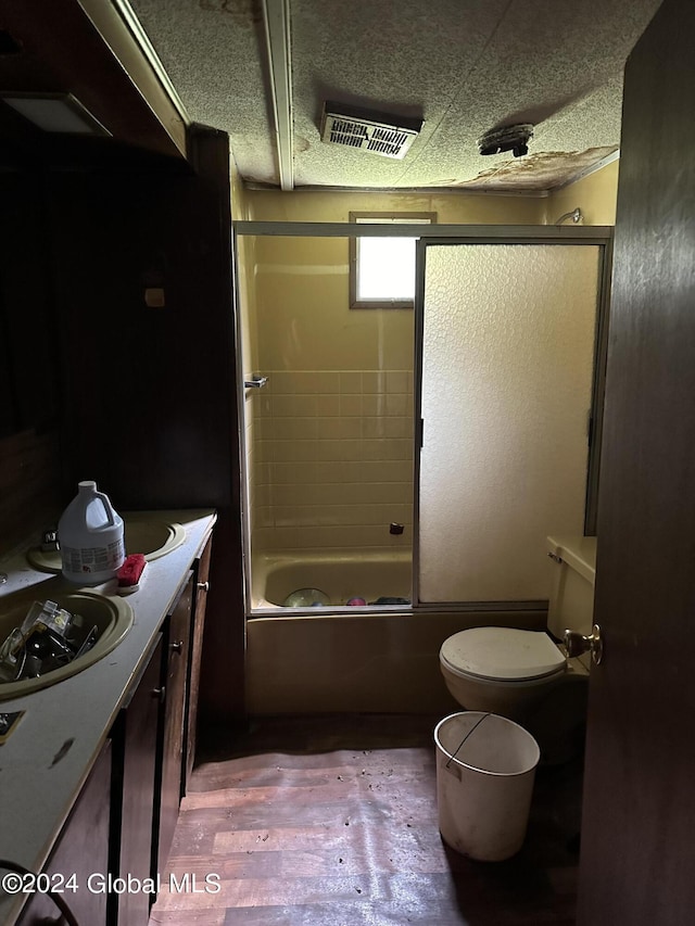 full bathroom with enclosed tub / shower combo, vanity, and toilet