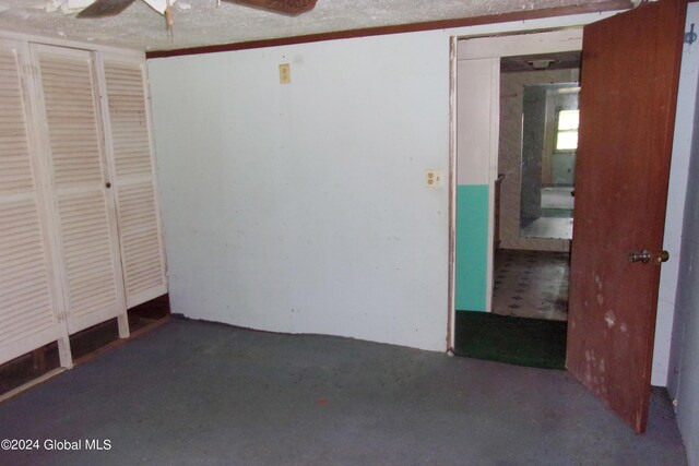 unfurnished bedroom with ceiling fan and a textured ceiling