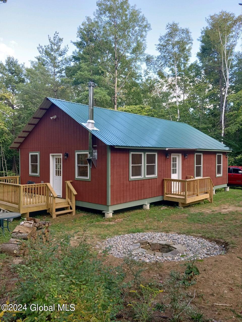 388 Pucker St, Warrensburg, NY 12885 - rear view of house featuring metal roof, a fire pit, and a deck