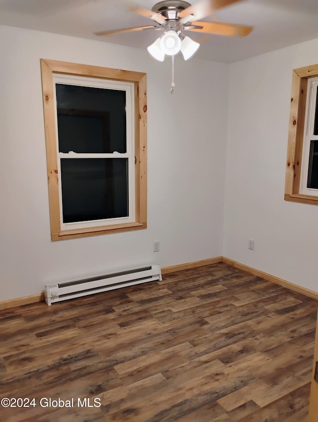 spare room featuring ceiling fan, dark wood-type flooring, and a baseboard heating unit