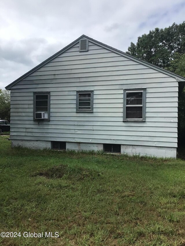 view of side of property featuring cooling unit and a yard