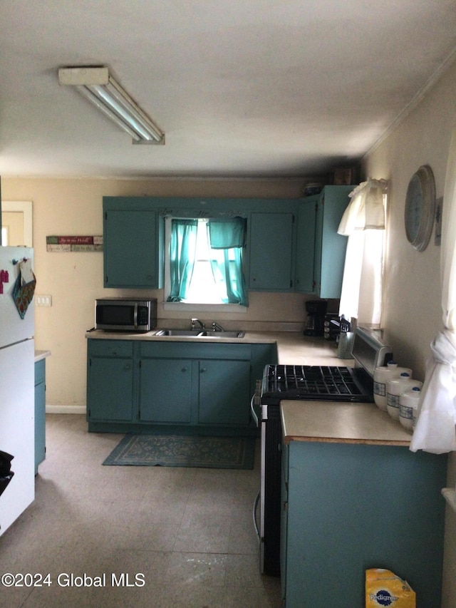 kitchen featuring sink, crown molding, range, and white fridge