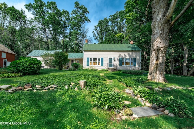 view of front of property featuring a front yard, metal roof, a chimney, and entry steps