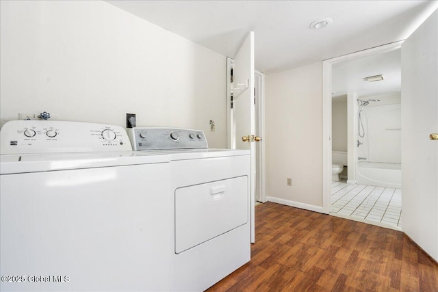 laundry area featuring laundry area, wood finished floors, baseboards, and washing machine and clothes dryer