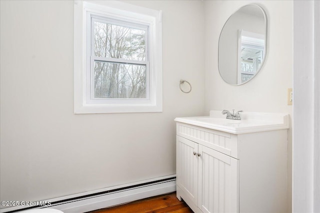 half bath with a baseboard heating unit and vanity