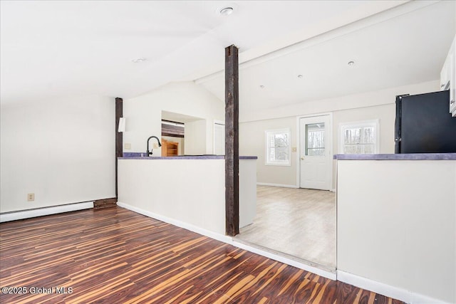 unfurnished living room featuring a baseboard heating unit, baseboards, lofted ceiling with beams, wood finished floors, and a sink