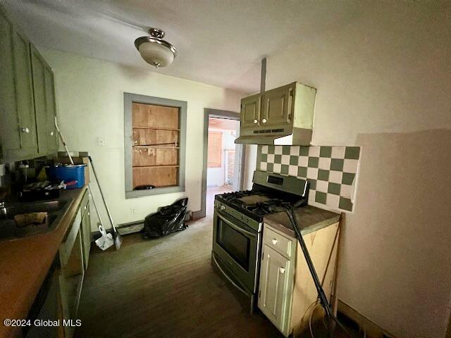 kitchen featuring sink, gas stove, green cabinetry, range hood, and decorative backsplash