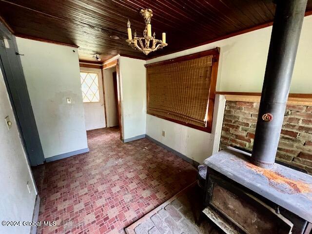 unfurnished dining area featuring wood ceiling, crown molding, and a notable chandelier