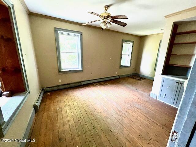 interior space with hardwood / wood-style flooring, ceiling fan, multiple windows, and ornamental molding