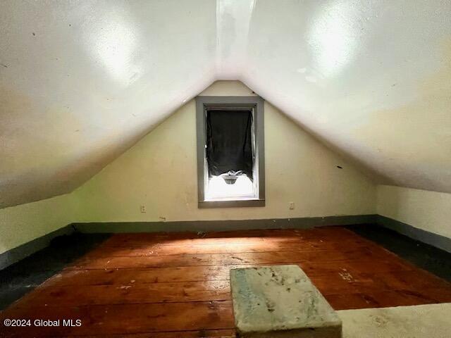 bonus room with dark wood-type flooring and vaulted ceiling