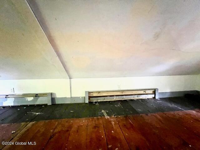 bonus room with dark wood-type flooring and vaulted ceiling