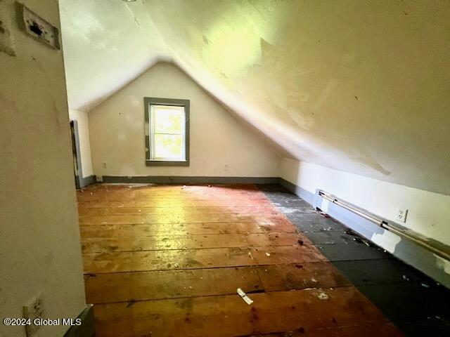 bonus room with wood-type flooring, vaulted ceiling, and a baseboard radiator