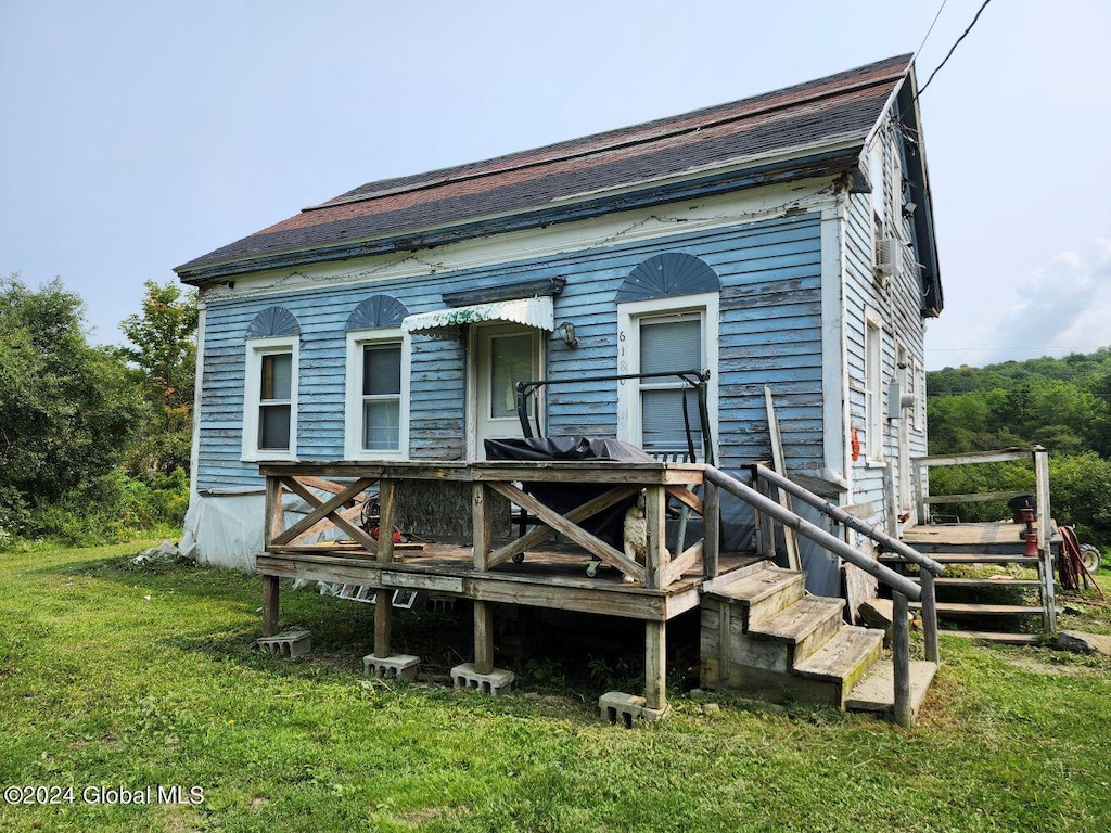 rear view of house featuring a deck and a lawn