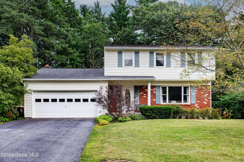 view of front of property with a garage, driveway, brick siding, and a front lawn