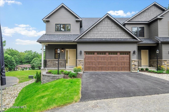 craftsman-style house featuring a porch, a garage, and a front yard