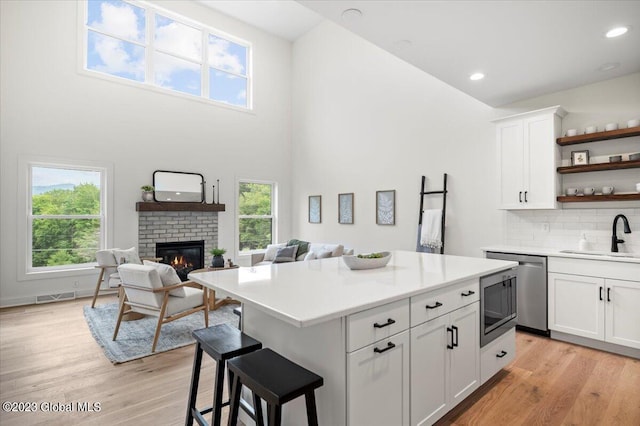 kitchen with sink, a fireplace, light hardwood / wood-style flooring, and a center island