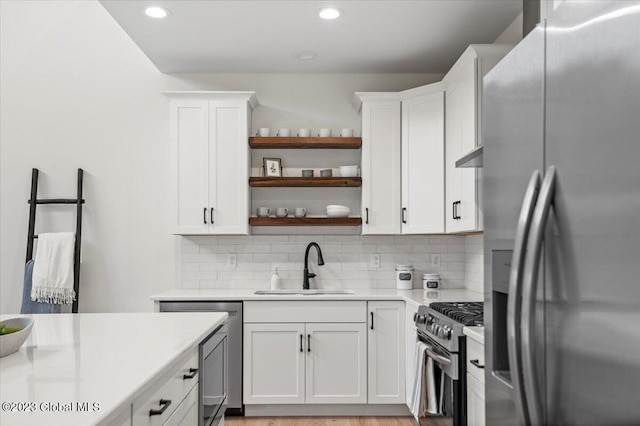 kitchen with light hardwood / wood-style floors, appliances with stainless steel finishes, decorative backsplash, and white cabinets