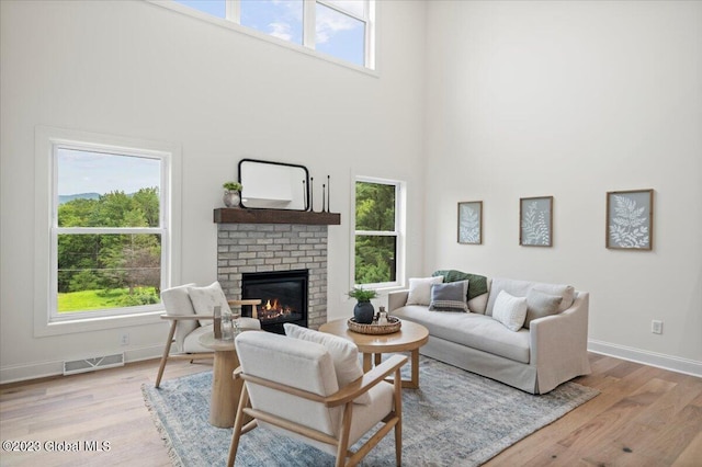 living room featuring a towering ceiling, a fireplace, and light hardwood / wood-style floors