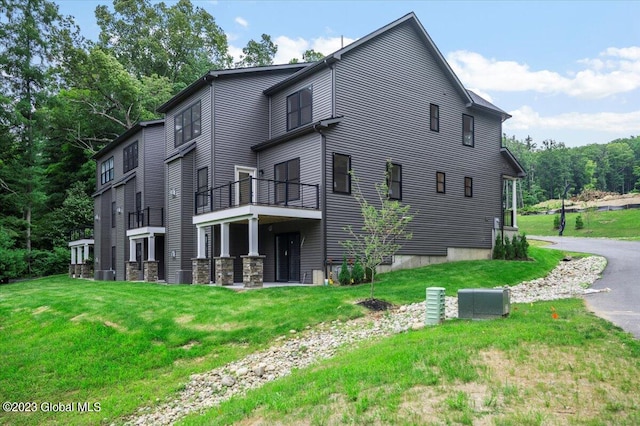 back of house with a balcony and a lawn