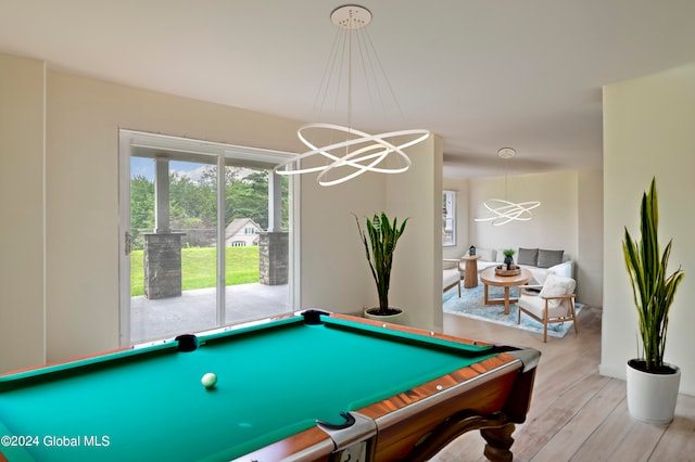 game room with a wealth of natural light, light hardwood / wood-style flooring, a notable chandelier, and pool table