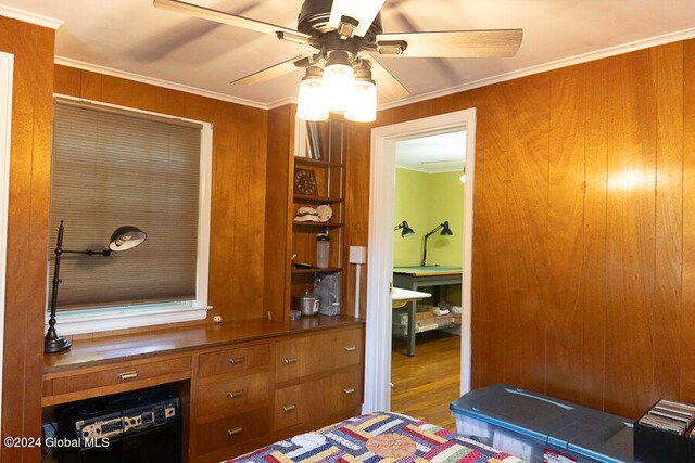 bedroom with wooden walls, ceiling fan, hardwood / wood-style floors, and crown molding