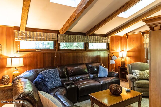 living room featuring vaulted ceiling with skylight, wood walls, and plenty of natural light