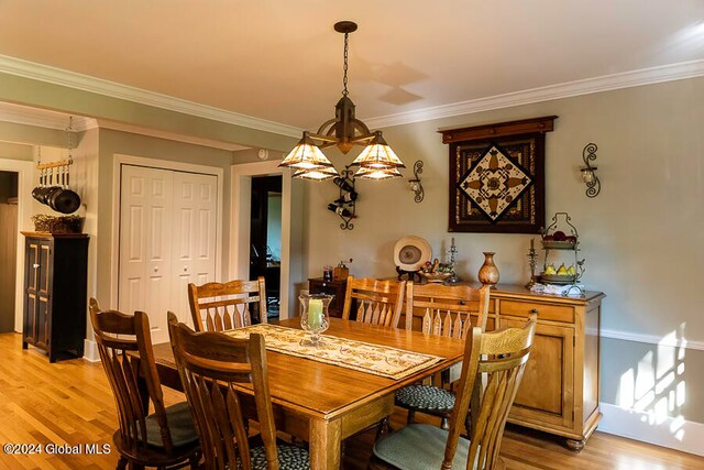 dining area with crown molding and light hardwood / wood-style floors