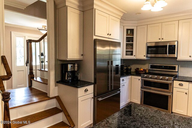 kitchen featuring white cabinets, stainless steel appliances, an inviting chandelier, crown molding, and decorative backsplash